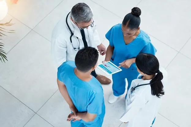 Nurse Leader Holds a Team Meeting in Hospital Lobby.